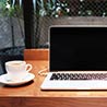 カフェでノートパソコンとコーヒーカップが置いてある写真